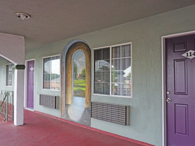 A photo of the exterior of a building with a purple door and a mural on the wall.