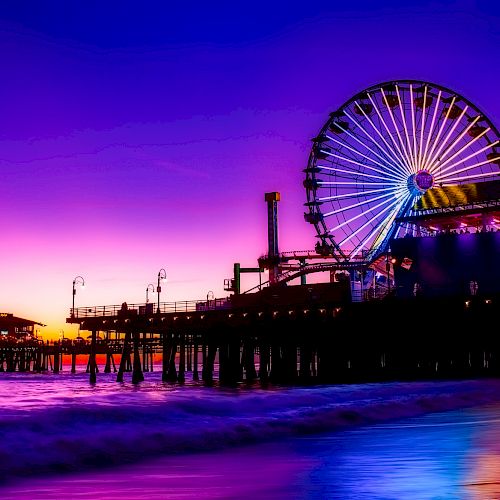 The image depicts a pier at sunset with a Ferris wheel, vibrant purple sky, and calm ocean waves, creating a picturesque, serene scene.