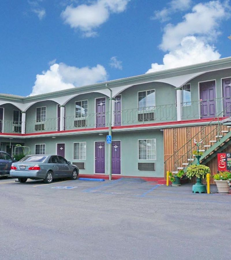 A two-story motel with a parking lot and a staircase leading to the second floor.
